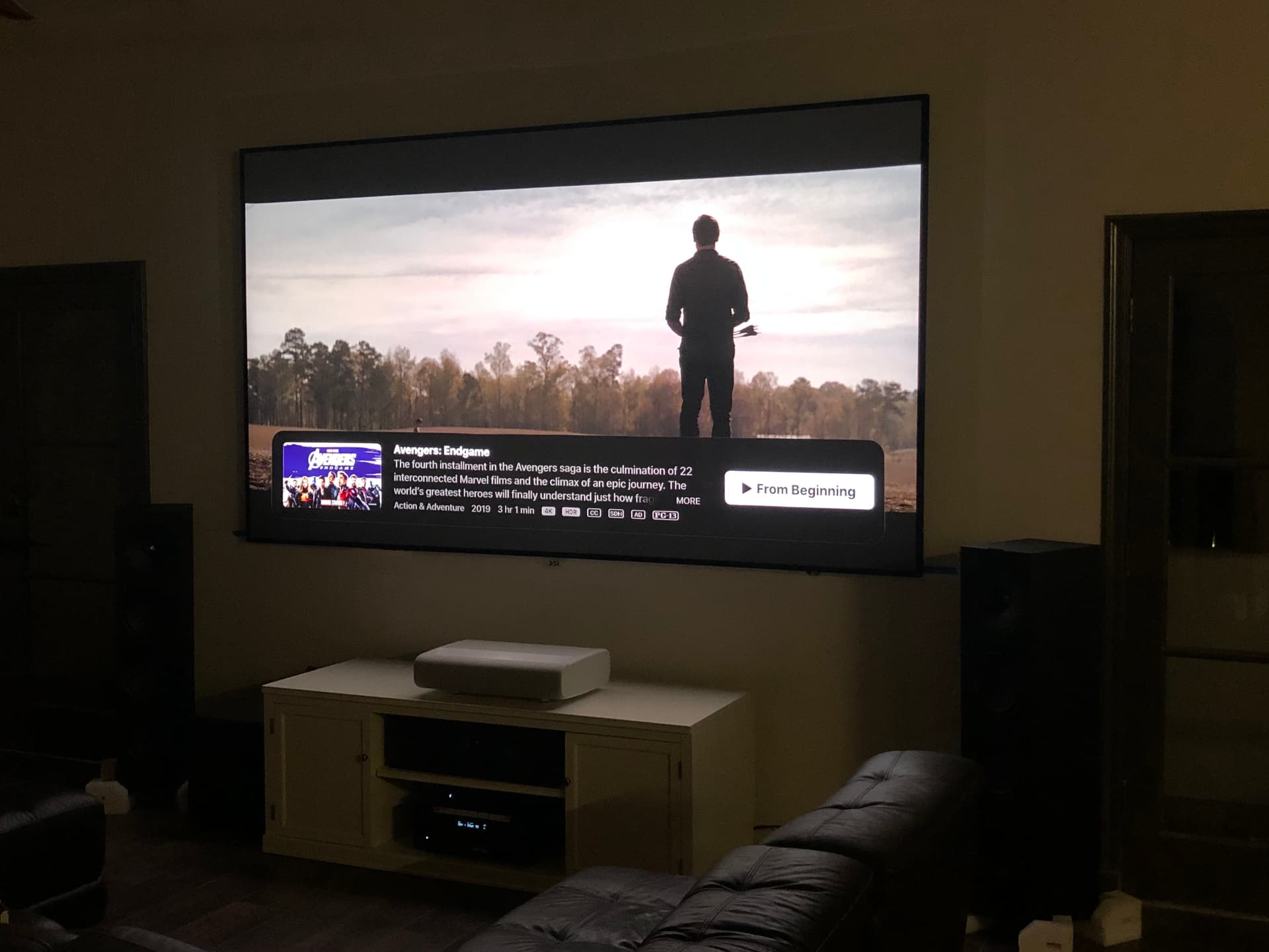 Modern living room with ultra-short-throw laser projector displaying 4K content on large screen