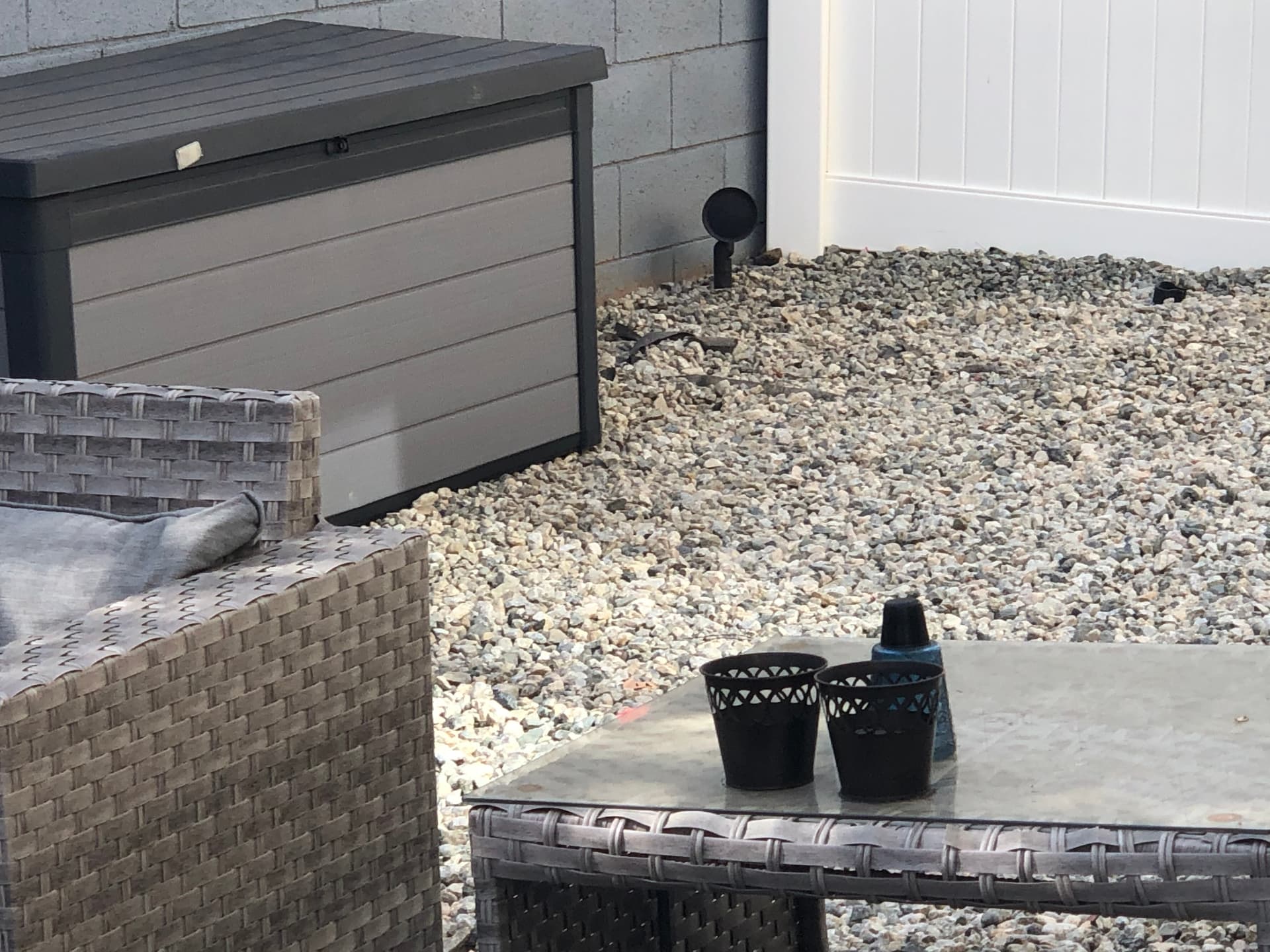 Outdoor patio seating area with wicker furniture, landscape speakers, and weatherproof equipment enclosure