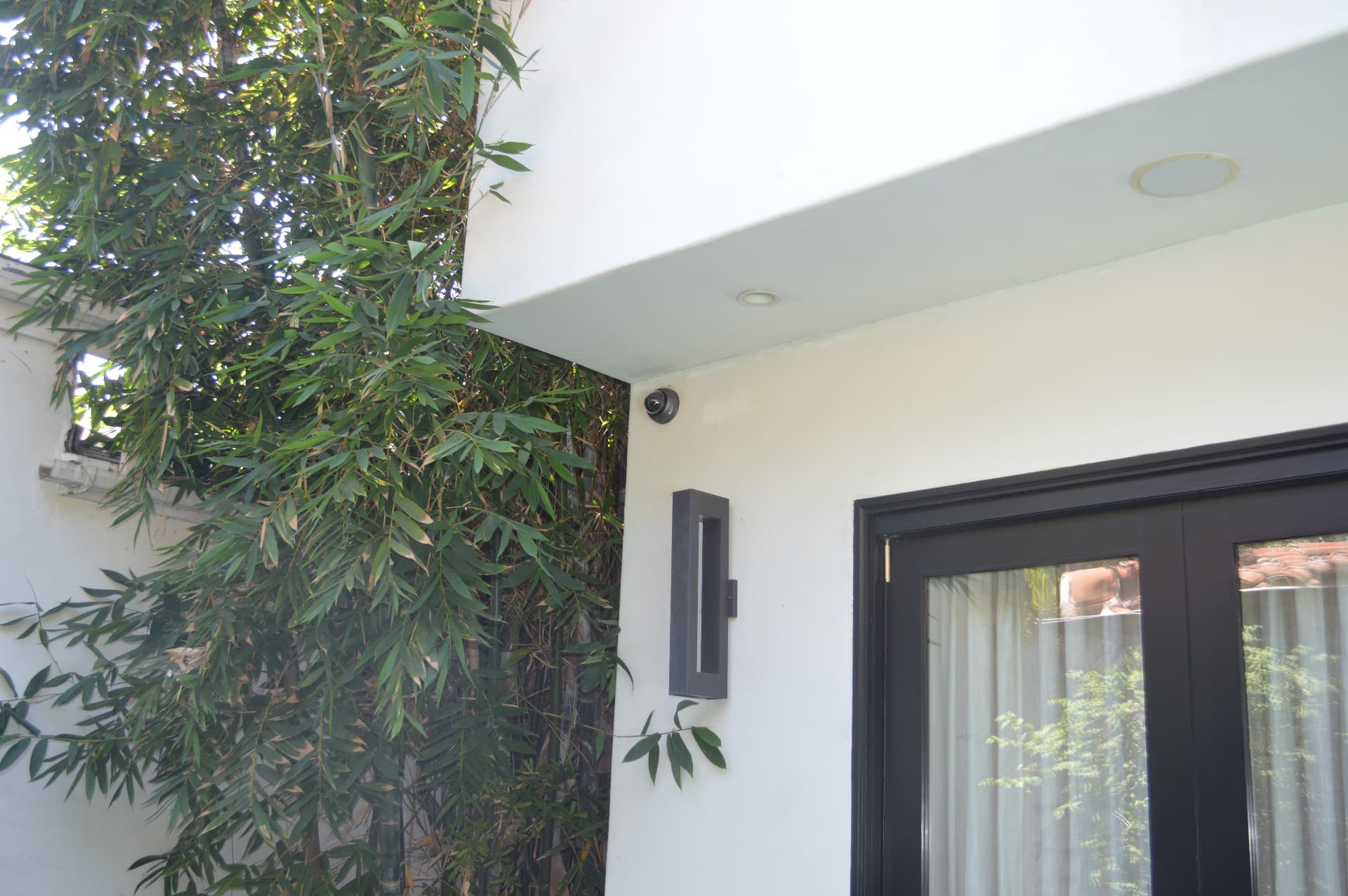Patio doors and bamboo landscaping with compact dome camera mounted under overhang